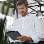 Empresário surpreso no escritório olhando para tablet digital - Marketing do Sistema de Gestão da Qualidade