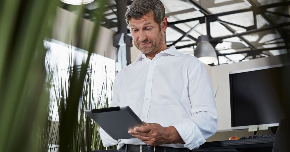 Empresário surpreso no escritório olhando para tablet digital - Marketing do Sistema de Gestão da Qualidade