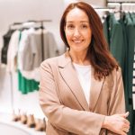Retrato de mulher de negócios adulto elegante em gerente de terno bege na loja de roupas - O que é Qualidade Gerencial?