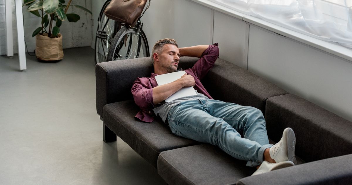 Você pode realizar seus sonhos - homem cansado deitado no sofá com laptop e dormindo em casa, escritório