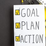 Como Colocar o Plano Estratégico em Ação? - vista superior objetivo plano ação notas com canetas no fundo escuro amarelo escritório sucesso negócio