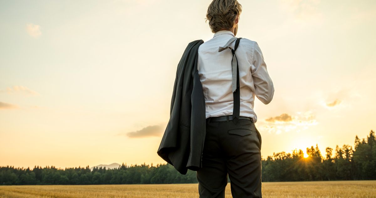 Jovem empresário bem sucedido em pé no campo de trigo olhando para o futuro - Como Descobrir sua Missão Pessoal?